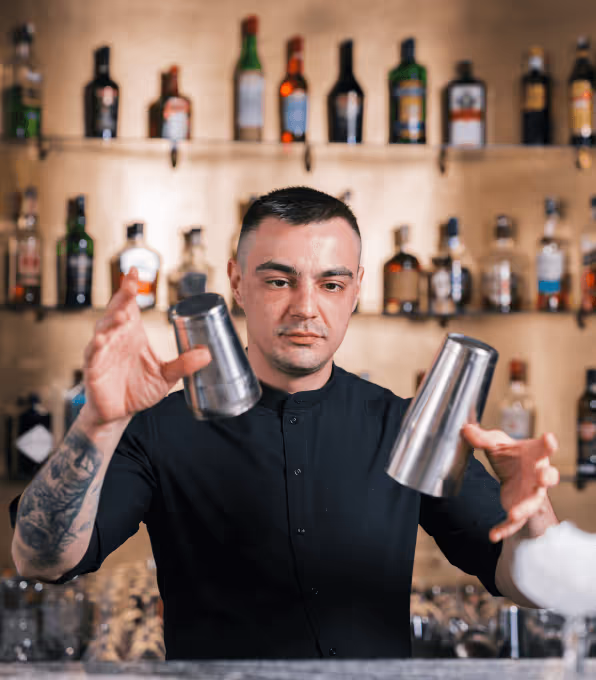 A bartender throws cups and drinks up in the air